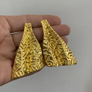 Gedetailleerd overzicht van gouden onregelmatige geometrische oorbellen in metaalstijl.