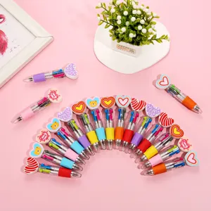 Detailed shot of cute multi-color ballpoint pens with heart toppers arranged on pink background.