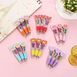 Detail shot of cute multicolored ballpoint pens with heart toppers on pink background.