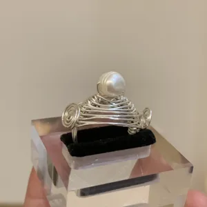 Nahaufnahme des handgefertigten Metall-Drahtrings mit Perlendetail auf Acrylständer.