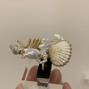 Nahaufnahme des handgefertigten Ozean-Rings mit Naturmuscheln Perlen und Golddraht.