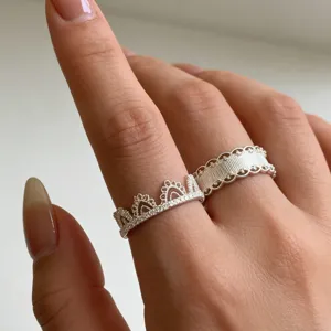 Close-up van twee stijlvolle zilveren ringen met een kroon pavé ontwerp en gestructureerde band.