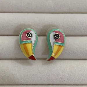 Kleurrijke geëmailleerde toekan oorknopjes, stijlvolle metalen dieren sieraden detail.