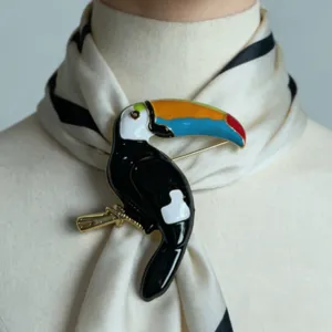 Gedetailleerd van een kleurrijke geëmailleerde toekan vogel broche op een chique sjaal.