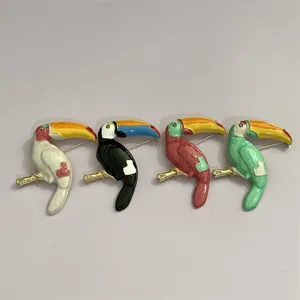 Close-up van vier kleurrijke emaille toekan vogel broches met levendige metalen pinnen.