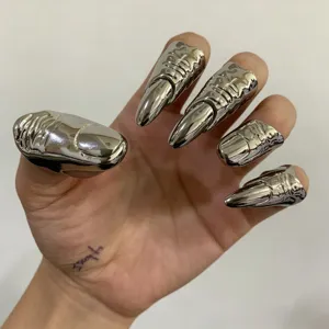 Gedetailleerde opname van zilveren metallische sneaker vingerklauw ringen, opvallende nagelsieraden.