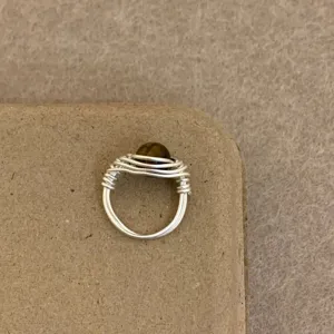 Close-up detail of handmade wire wrapped ring featuring a natural tiger eye stone bead.