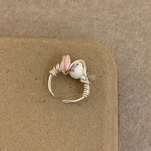 Close-up detail shot of a handmade wire-wrapped ring featuring ceramic beads and clear crystals.
