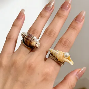 Vue rapprochée d'une bague coquillage naturelle avec de délicats détails de perles et de fil.