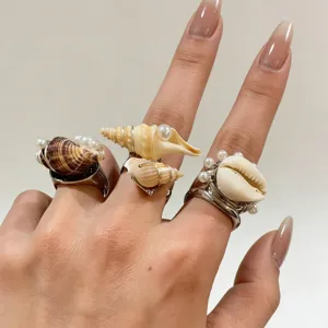 Vue détaillée de bagues coquillage et perles faites main, bijoux style océan en fil métallique.