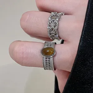 Zilverkleurige opengewerkte stapelbare ringen in vintage stijl met tijgeroogsteen detail.