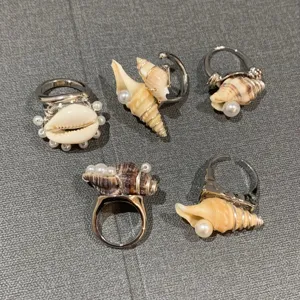 Détail de bagues en coquillage naturel et perles, style océan, bijoux de vacances uniques.