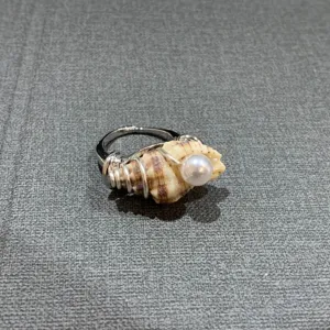 Gros plan détaillé de bague en perle de coquillage faite main avec texture naturelle et fil.