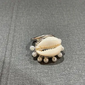 Vue de détail en gros plan d'une bague coquillage style océan faite main avec de petites perles.