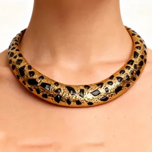 Vista cercana detallada de un collar gargantilla grueso vintage dorado con manchas de leopardo.