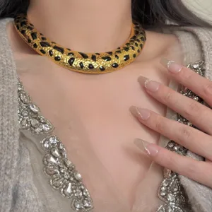 Detalle de collar gargantilla rigida con elegante estampado de leopardo esmaltado en oro.