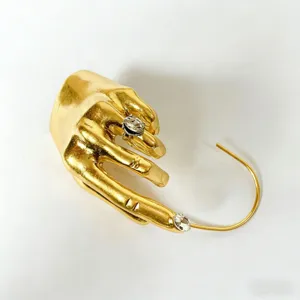 Auricolare a mano in metallo dorato con strass scintillanti, gioiello surrealista unico.