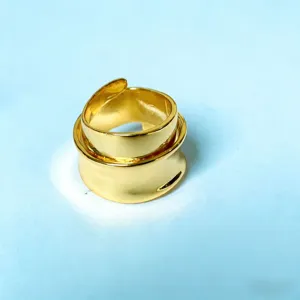 Goudkleurige open metalen ring, brede gelaagde vormgeving, minimalistisch sieradendetail.