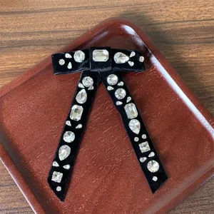 Dettaglio spilla fiocco in velluto nero con strass di cristallo, accessorio elegante per camicie.