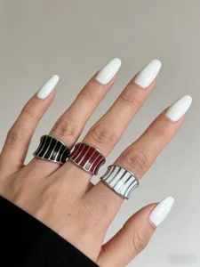 Primo piano dettagliato di anelli aperti larghi smaltati a righe, eleganti gioielli da dito.