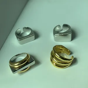Primo piano di anelli aperti in metallo minimalista di tendenza con elegante design geometrico.