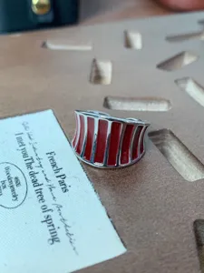 Primo piano di anello aperto largo in metallo e smalto rosso dal design unico e chic.