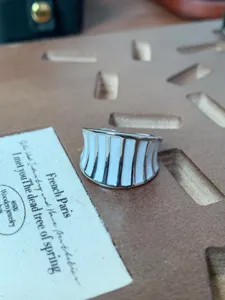 Vista dettagliata dell'anello aperto in metallo con eleganti strisce di smalto bianco.