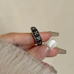 Primo piano dell'anello smaltato con croce gotica che mostra dettagli floreali in argento.