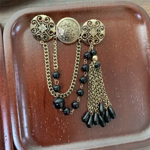 Vintage retro brass tone metal brooch with black beads and chain tassels for women.