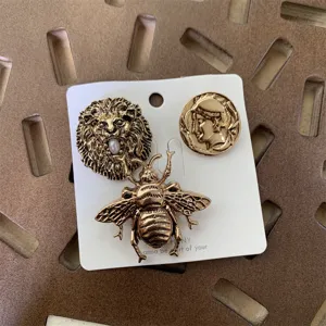 Vintage retro gold-tone metal brooch pin set featuring lion head, bee, and coin relief.