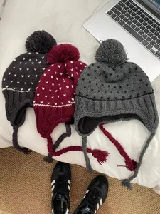 Detail view of Korean cute pom-pom knit hat with warm earflaps and thick fleece lining for winter.