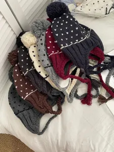 Close up view of cozy knit pom pom earflap beanies in various autumn winter colors.