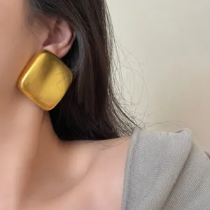 Vue rapprochée détaillée montrant la texture et le design des boucles d'oreilles carrées.