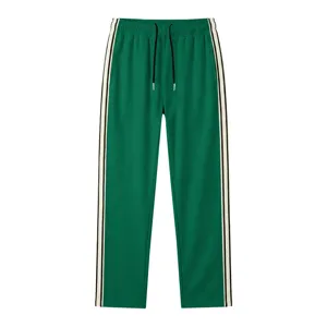 Détail de pantalon de survêtement vert avec bandes latérales contrastées et cordon de serrage.