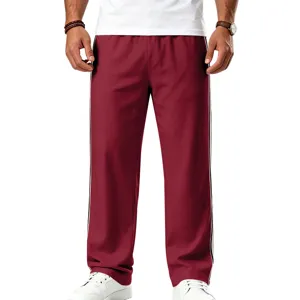 Vue detaillee de pantalon de survetement homme, tissu bordeaux avec bandes laterales.