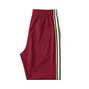 Vue détaillée du pantalon de survêtement homme bordeaux avec bandes contrastées sur les côtés.