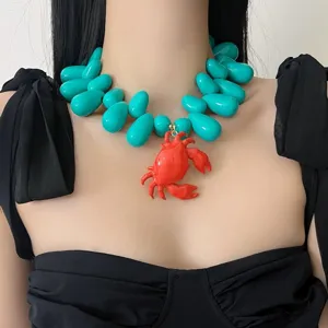 Vue détaillée du collier de perles turquoise exagéré avec un pendentif crabe rouge audacieux.