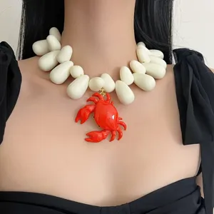 Gros plan sur le pendentif crabe rouge vif et le collier statement en perles blanches.