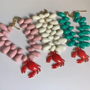 Vue détaillée de colliers pendentifs crabe vibrants en perles rose, blanc et turquoise.