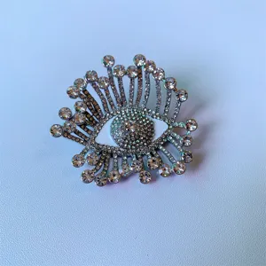 Détail de la broche œil maléfique en strass scintillants, design élégant en cristal et émail.