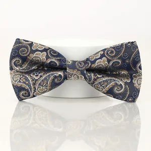 Close-up of a navy blue bow tie with exquisite gold and white paisley jacquard pattern.