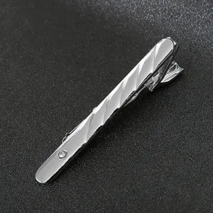 Close-up detail of silver metal tie clip with diagonal stripes and crystal accent.