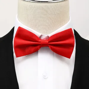 Gros plan d'un nœud papillon rouge vif assorti à une chemise blanche et un costume noir.