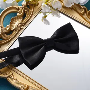 Detailaufnahme einer eleganten schwarzen Satin-Fliege auf einem dekorativen goldenen Tablett.