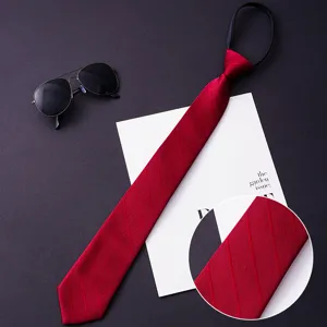 Detail view of a classic red zip necktie with fine twill texture, paired with stylish props.
