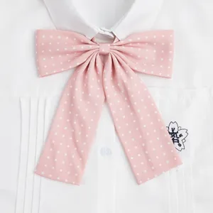 Primo piano dettagliato di un dolce fiocco rosa a pois sul colletto di una camicia.