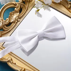 Detaillierte Ansicht einer eleganten weißen Satin-Fliege auf einem goldenen Spiegel für die Hochzeit.