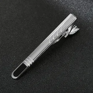 Close-up detail of a sleek silver metal men tie clip with black accent and striped texture.