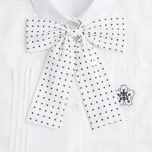 Camicia da uniforme JK bianca con papillon a pois e stemma ricamato sulla tasca.