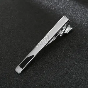 Close-up detail of silver metal tie clip with geometric grid pattern and black inlay.